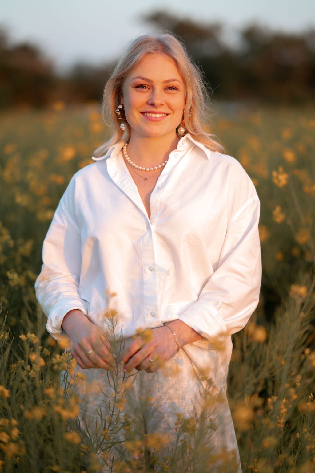 Chantal in een wit overhemd in een veld met gele bloemen, bij zonsondergang