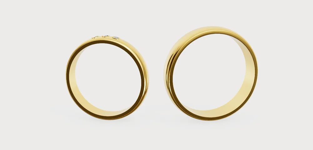 Twee handgemaakte trouwringen in geelgoud, de ene met drie diamanten: het startontwerp van de Ring Designer