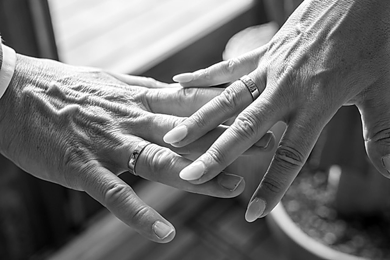 Twee generaties handen met trouwringen, zwart-wit